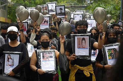 Anti-coup protesters holding pictures of those who died during a protest against the military offer prayers for them, in Yangon, Myanmar (Photo | AP)