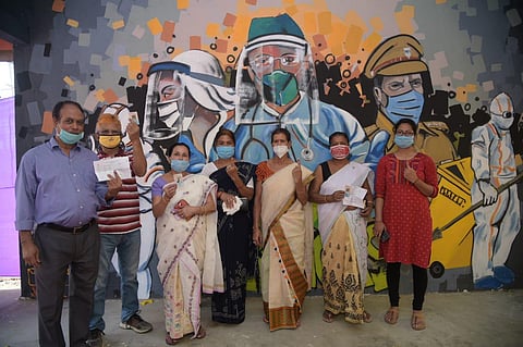 Voters in Assam pose at a polling booth, in front of wall art dedicated to COVID warriors. (Photo | Express)
