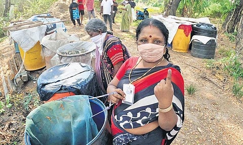 A voter in Ramanthuruth shows her inked finger as she stands near the barrels used by residents of the islet to collect drinking water.  Lack of drinking water remains a major concern | Albin Mathew