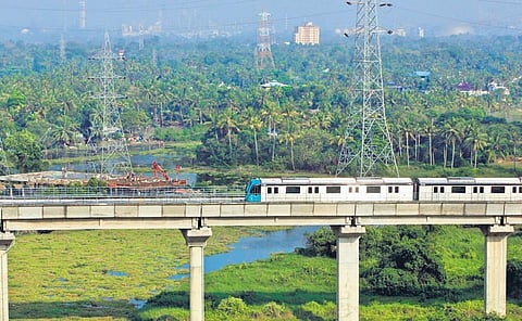 A metro train passes by the construction site of a boat jetty, part of the Water Metro project, near Vyttila Mobility Hub.