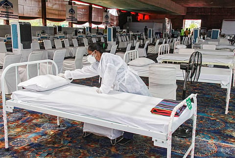 A worker prepares a bed at an oxygen centre for COVID-19 patients, operated by Hemkunt Foundation, in Gurugram, Wednesday, May 12, 2021. (Photo | PTI)