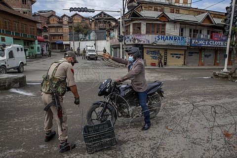 A Kashmiri motorcyclist requests to an Indian policeman to let him pass a temporary check point during lockdown to curb the spread of coronavirus. (File Photo | AP)