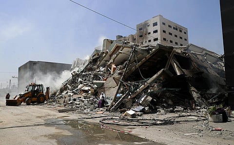 Workers clear the rubble of a building that was destroyed by an Israeli airstrike that housed The Associated Press, broadcaster Al-Jazeera and other media outlets, in Gaza City. (Photo | AP)