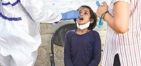 A young girl gives her swab samples for a Covid test at a Primary Health Centre in  Bengaluru on Monday | VINOD KUMAR T