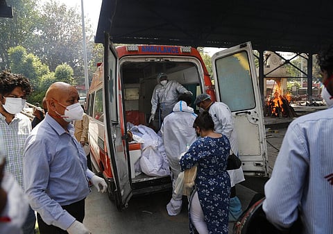Health workers prepare to take out from an ambulance bodies of six people who died of COVID-19 for cremation, in New Delhi. (Photo | AP)