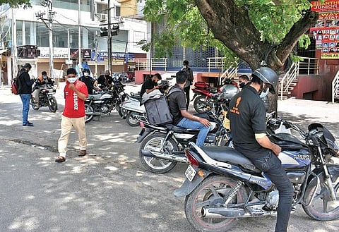 Food delivery agents wait for their turn to collect food packages for customers at a restaurant near Tolichowki in Hyderabad on Thursday | S Senbagapandiyan