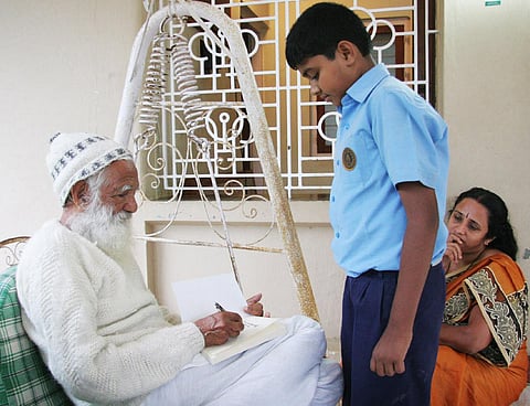 Sunderlal Bahuguna signing an autograph for a boy at the house of Rathnakar at Kainatty, Wayanad. (Photo | EPS)