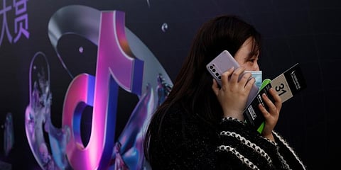 A woman speaks on her phone near the logo for Douyin in Beijing on Wednesday, March 31, 2021.  (Photo | AP)