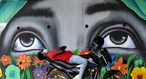 A food delivery boy takes a nap on his two-wheeler, under the Hi-Tech city MMTS flyover in Hyderabad. (Photo | S Senbagapandiyan, EPS)