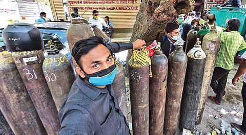 Family members of Covid-19 patients wait outside an oxygen-filling centre to refill their empty cylinders in New Delhi on Monday. (Photo | PTI)