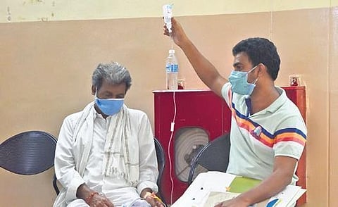 A patient infected by black fungus waits for a bed at Government ENT Hospital, Koti, while his attendant holds a saline bottle, in Hyderabad on Wednesday.