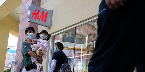 A woman and child wearing masks pass by a H&M store in Beijing on Thursday, June 3, 2021.  (Photo | AP)