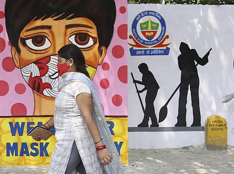 A woman walks past a wall mural on raising awareness about wearing facemasks, amid the ongoing COVID-19 pandemic in New Delhi, Friday, June 18, 2021. (Photo | PTI)