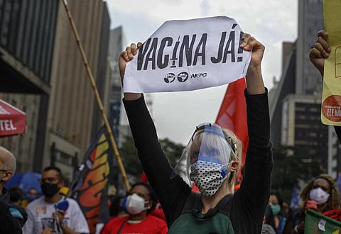 A demonstrator holds a sign that reads in Portuguese; ''Vaccine now', during a protest against Brazilian President Jair Bolsonaro and his handling of the COVID-19 pandemic in Sao Paulo. (Photo | AP)
