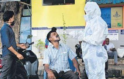 A health worker collects swab samples of a man near KSR Railway Station in Bengaluru on Friday  | ashishkrishna hp