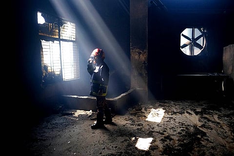 A firefighter communicates with his colleagues on a walkie talkie inside the burnt food and beverage factory in Rupganj, outside Dhaka, Bangladesh, Friday, July 9. (Photo | AP)