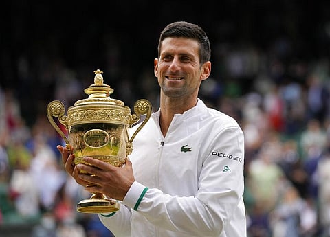 Serbia's Novak Djokovic holds the winners trophy as he poses for photographers after he defeated Italy's Matteo Berrettini in the men's singles final on day thirteen of the Wimbledon. (Photo | AP)