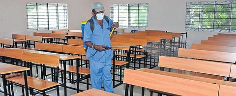 A staffer sanitises a classroom at a school in Tumakuru, prepping it for SSLC exams, on Friday | Express