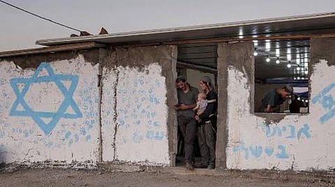 Israeli settlers stand through the doorway of a shack in the newly-established wildcat outpost of Eviatar near the northern Palestinian city 
