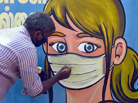 An artist paints 'No mask No Entry' graffiti at Chennai Central Railway station. (EPS | Martin Louis)