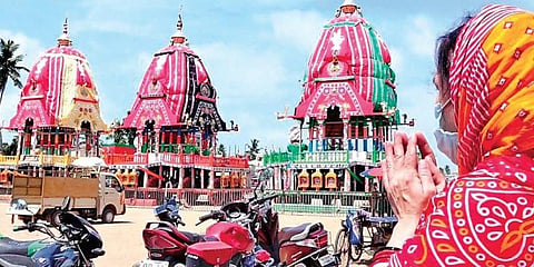 A woman offers prayers from a distance near the Gundicha temple where the three chariots are parked, on Monday. (Photo | EPS)