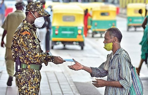 A BBMP marshal gives away a mask to a man in Bengaluru on Tuesday. The city reported 715 fresh Covid-19 cases | shriram bn