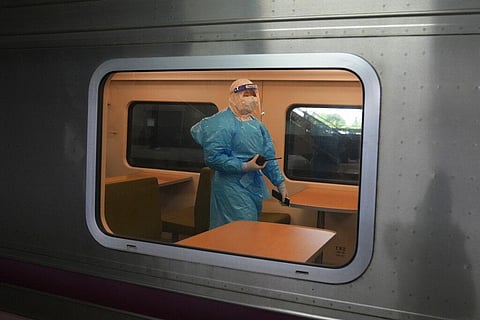 A Thai health worker with protective gear walks inside a train as the train prepares to carry a group of COVID-19 patients to their hometowns. (Photo | AP)