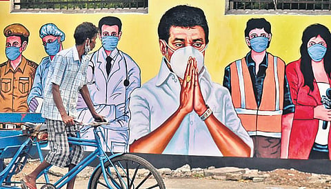 A man with his mask well down the chin rides near a wall painting of CM MK Stalin and frontline workers appealing the public to wear masks, at Kasimedu. (File photo| P Jawahar, EPS)