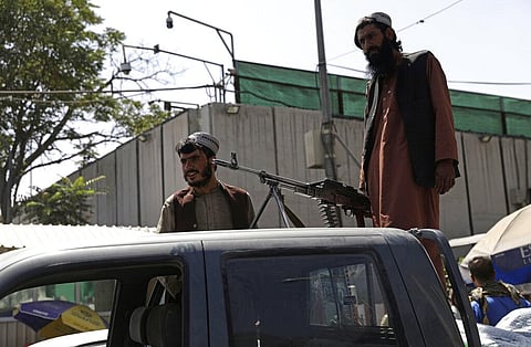 Taliban fighters stand guard on the back of vehicle with a machine gun in front of main gate leading to Afghan presidential palace. (Photo | AP)