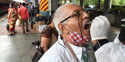 A healthcare worker takes a swab sample of a passenger during the COVID-19 test. (File Photo| ANI)