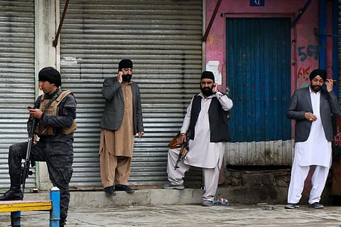 An Afghan security personnel (L) stands along with Sikhs near the site of an attack to a Sikh temple in Kabul on March 25, 2020. (File Photo | AFP)