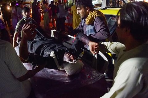 Medical and hospital staff carry an injured man out of a car for treatment after two blasts, which killed at least five and wounded a dozen | AFP