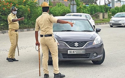 Police personnel stop a car entering Karnataka at Attibele check-post to check for documents, in Bengaluru on Monday.