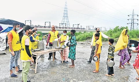 Children getting free food distributed by Civil Defence Volunteers  near Shastri Park metro station on Monday. (Photo | EPS/Parveen Negi