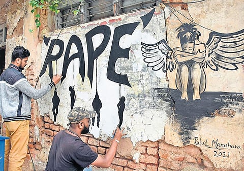 Mysuru artists Rahul and Sumanth Gowda paint a wall with a message demanding stricter punishment to those who commit heinous crimes like rape, in Mysuru on Sunday. (Photo  | Udayshankar S, EPS)