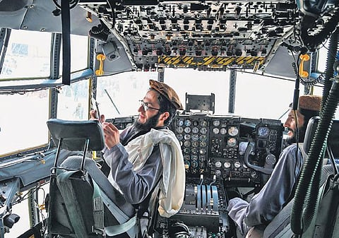 Taliban fighters in the cockpit of an Afghan Air Force plane at Kabul airport  | ap/afp