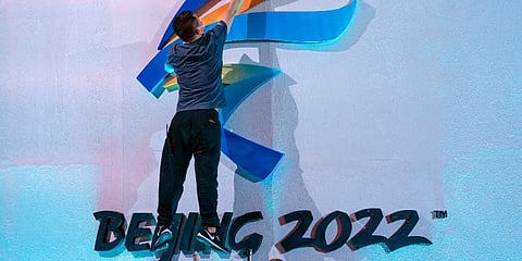 A crew member leaps to fix a logo for the 2022 Beijing Winter Olympics before a launch ceremony to reveal the motto for the Winter Olympics and Paralympics in Beijing, Sept. 17, 2021. (Photo | AP)