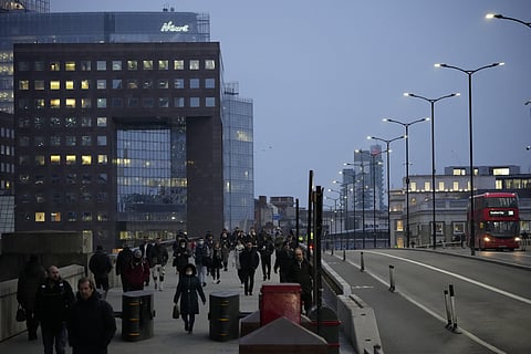 Workers walk over London Bridge towards the City of London financial district during the morning commute, in London, Monday, Jan. 24, 2022. (Photo | AP)