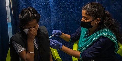A schoolgirl reacts as she receives vaccination for COVID-19 at a vaccination center (Photo | AP)