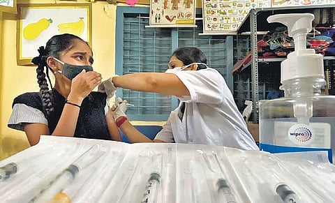 A health worker vaccinates a student against Covid-19 in a school in Bengaluru on Monday. The city saw 1,041 fresh cases. (Photo | EPS)