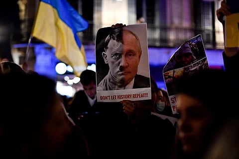 A demonstrator holds a sign depicting Adolf Hitler and Russia's president Vladimir Putin during a protest against Russia's military operation in Ukraine, in Barcelona on February 24, 2022.  (Photo | A