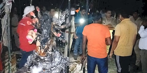 Police personnel and locals at the site after a fire broke out in a community Durga Puja pandal during the festival celebrations, in Bhadohi. (Photo | PTI)