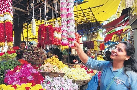 A woman purchases flowers and other puja materials ahead of Ayudha Puja and Vijayadashami festival at Gandhi Bazar in Bengaluru on Monday | Shashidhar Byrappa