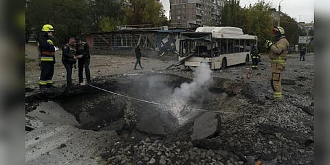 Firefighters and police officers work on a site where an explosion created a crater on the street after a Russian attack in Dnipro, Ukraine. (File Photo | AP)
