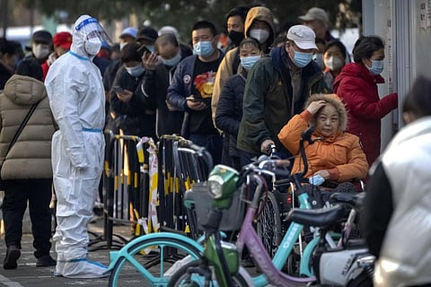 People wearing face masks wait for COVID-19 tests at a coronavirus testing site in Beijing (Photo | AP)
