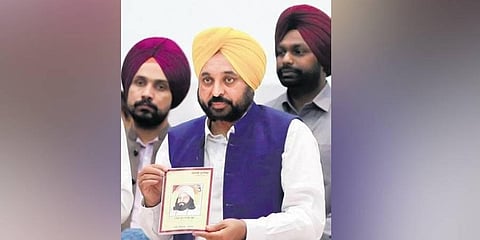 Bhagwant Mann releases a book at an event held to promote Punjabi language in Amritsar on Saturday. (Photo | PTI)