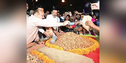 CM Basavaraj Bommai gives groundnuts to customers at the  Kadalekai Parishe in Basavanagudi on Sunday evening