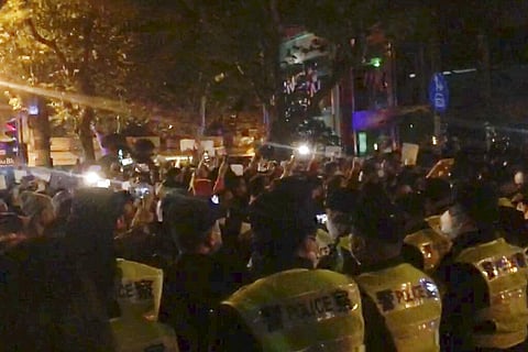 In this image from video obtained by The Associated Press, police, foreground, watch protesters in Shanghai on Saturday. (Photo | AP)