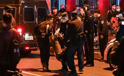 A man is arrested while people gathering on a street in Shanghai on November 27, 2022, where protests against China's zero-Covid policy took place. (Photo | AFP)
