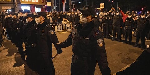 Chinese policemen form a line to stop protesters marching in Beijing. (Photo | AP)